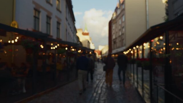 Blurred pedestrians walking along lively city street with warm caf lights and evening sky