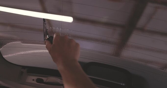 Car tinting windows services - Worker specialist apply tint foil on car window in workshop video