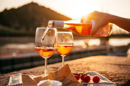 Pouring rose wine in summer sunshine during a outdoors party or a picnic.