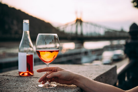 Hand holding glasses of rose wine in summer sunshine during a outdoors party or a picnic.