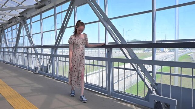 A Caucasian woman with cerebral palsy walks across a pedestrian bridge.