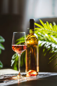 Chilled blush rose wine bottle and glass on table. Sunny summer patio relaxation and Mediterranean lifestyle outdoor dining concept.