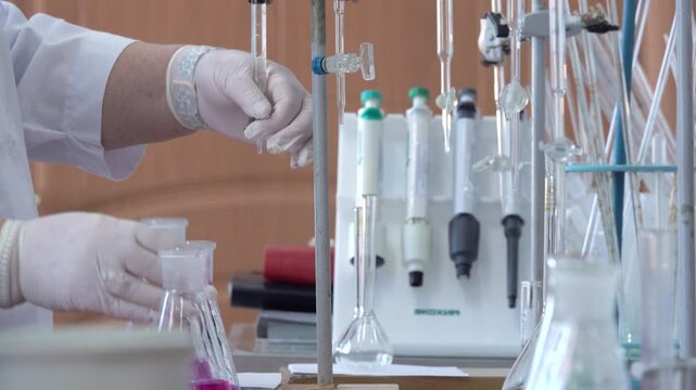 Close-up footage of a laboratory experiment with test tubes and glassware, featuring bubbling and mixing liquids. Scientific research process in a modern lab environment, showcasing chemical reactions