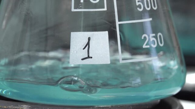 Close-up footage of a laboratory experiment with test tubes and glassware, featuring bubbling and mixing liquids. Scientific research process in a modern lab environment, showcasing chemical reactions