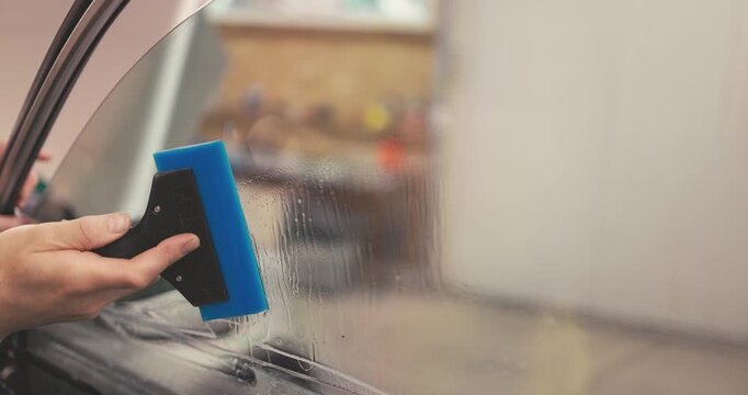 Professional Car tinting services for windows - Worker specialist apply tint foil on car window in workshop
