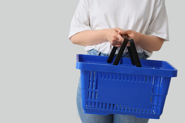 Fototapeta na wymiar Woman with blue shopping basket on grey background