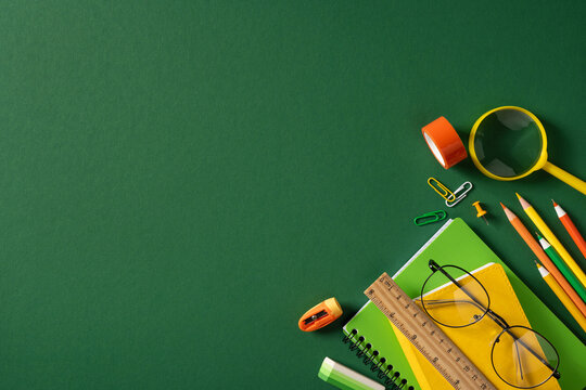 Back to school flat lay with green and yellow stationery, pencil, notebook, ruler and glasses
