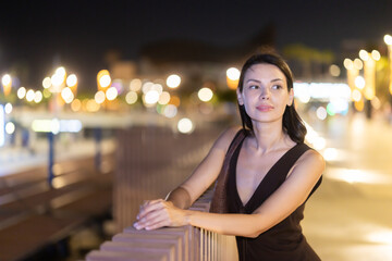 Naklejka premium Woman walks in vicinity of Citadel park, spend time in public urban space. Atmosphere of relaxation, idleness, entertainment. Electric street lighting, night life in big city .