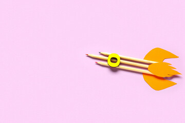 Fototapeta premium Rocket made of pencils, paper and wooden letter on pink background