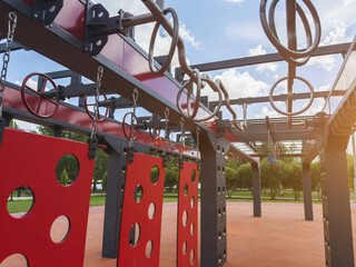 Outdoor obstacle course with hanging rings, monkey bars, suspended panels on modern fitness playground designed for OCR sport, ninja training, functional workout, endurance, strength, agility © Evgeniia Primavera