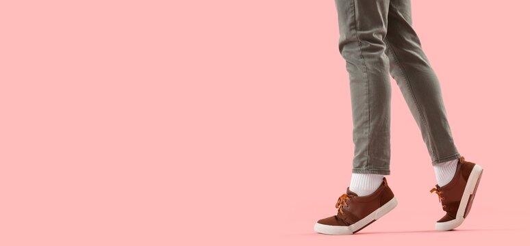 Person walking in brown sneakers on pink background