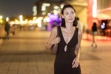 Naklejka premium Woman walks in vicinity of Passeig de Sant Joan, spend time in public urban space. Atmosphere of relaxation, idleness, entertainment. Electric street lighting, night life in big city