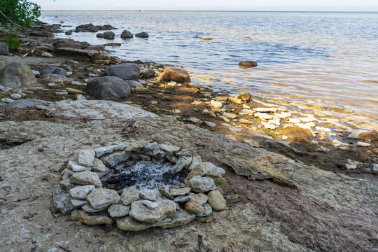 Abandoned fire ring on Baltic Sea beach beside rocky coastline
