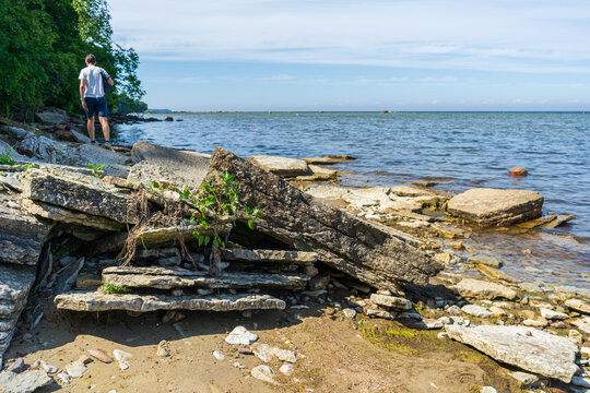 Hiker walking along rocky Baltic Sea shore on summer coastal trail