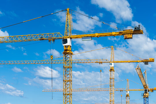 Close view of tower cranes against blue sky for construction site engineering and property development