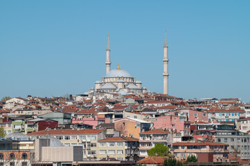 Fototapeta premium horizontal photo of a cityscape view of a ottoman mosque in a hill surrounded by buildings with a clear sky.