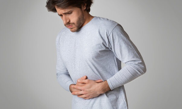 Young man hands on stomach, having bad aches pain. Food poisoning, influenza, cramps