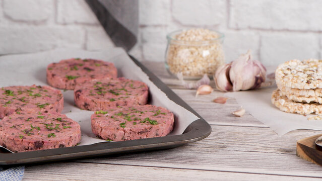 Raw vegan vegetable burger patties on a baking sheet with ingredients