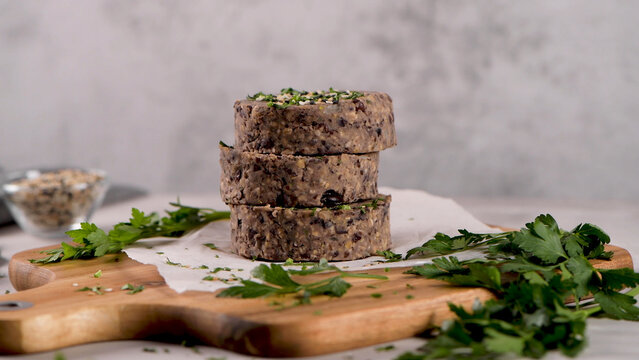 Stack of Raw Vegan Black Bean Burger Patties on a Wooden Cutting Board