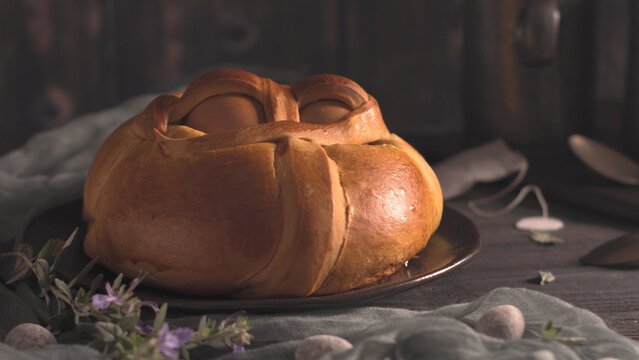 Traditional Portuguese Easter bread with baked eggs on a dark rustic table