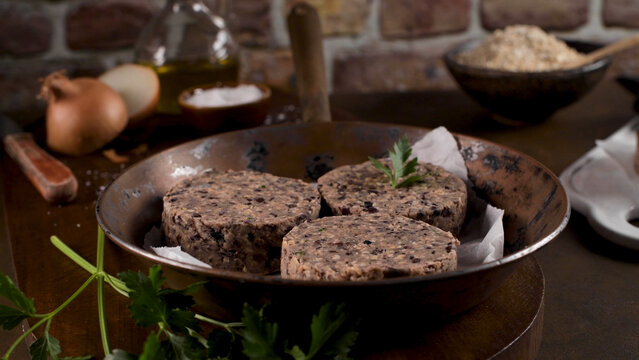 Raw black bean burger patties in a rustic copper skillet