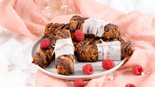 Homemade Granola Bars Drizzled with Chocolate and Garnished with Fresh Raspberries
