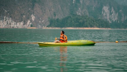 Fototapeta premium Woman kayaking on khao sok lake water, enjoying refreshing active travel vacation
