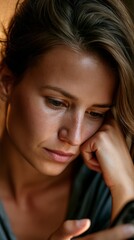 Fototapeta premium Woman looking down with hand on cheek, deep in thought or sadness