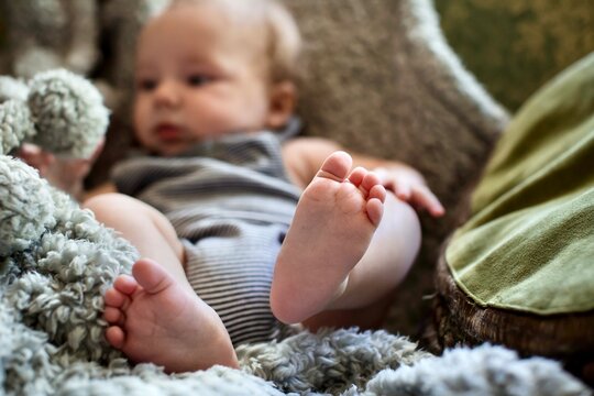 Close-up of a Baby Boy sitting barefoot on a Furry Blanket on the Sofa