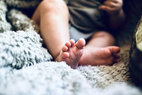 Close-up of a baby boy's bare feet on a Furry Blanket on a Sofa