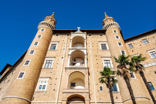 Ducal Palace of Urbino showcasing its iconic Torricini towers and historic brick facade under a clear blue sky, capturing the grandeur of Italian Renaissance
