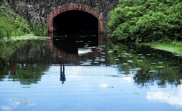 Reflection  in a lake of a person standing on a bridge