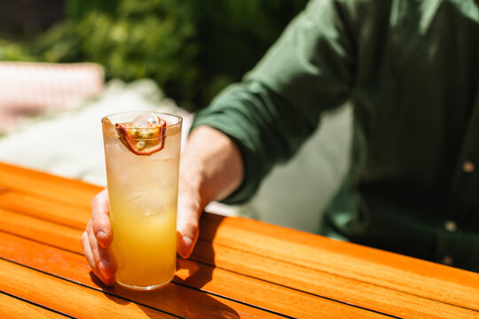 Close-up of a man sitting at a garden table drinking an iced passion fruit lemonade on a summer day
