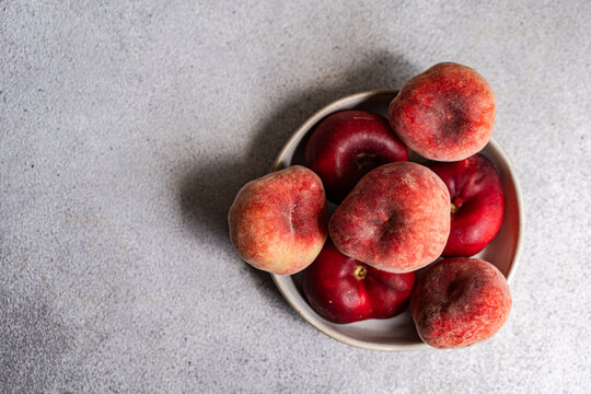 Close-up overhead view of a bowl of fresh ripe donut peaches on a table