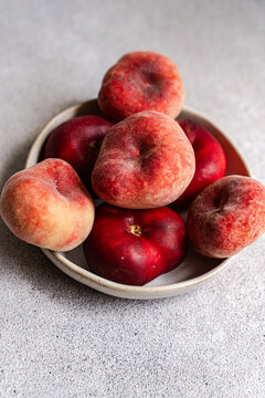 Close-up of a bowl of fresh ripe donut peaches on a table