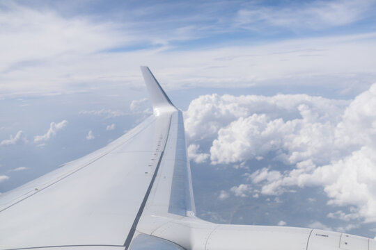 View through a window of an airplane wing flying through the clouds