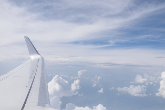View through a window of an airplane wing flying through the clouds