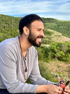 Close-up side view of a smiling man Sitting on a Metal Bench holding his sunglasses at Sunset Point on the Wild Rose Loop Trail, North Salt Lake, Salt Lake City, Utah, USA