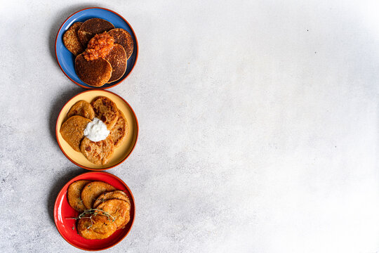 Overhead view of three different coloured plates with Potato pancakes (draniki) and various sauces