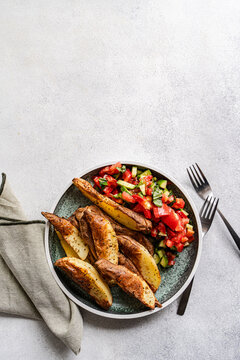 Overhead view of a plate of Baked potato wedges with pico de Gallo on a table