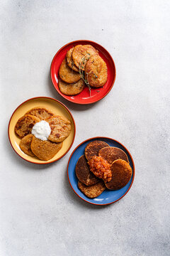 Overhead view of three different coloured plates with Potato pancakes (draniki) and various sauces