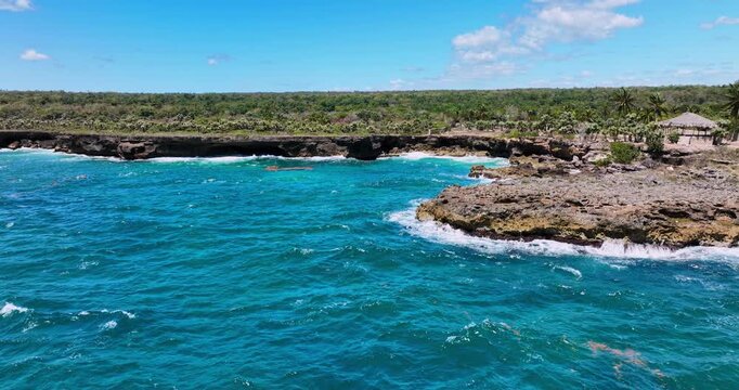Tropical rocky coastline with turquoise ocean waves and gazebo on a sunny day Dominican republic