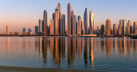 Obraz premium Modern buildings with gold reflections of the sunset on Dubai Marina, bay view from Palm Jumeirah, UAE.