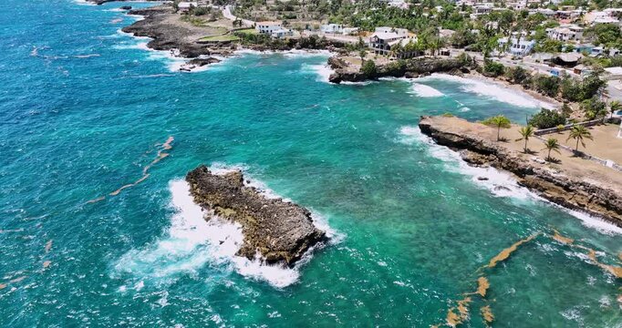 Aerial view of tropical rocky coastline of with sea caves and crashing waves against cliffs on the shore