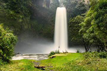 Fototapeta premium Long exposure photograph of a waterfall with green plants around it in Ecuador