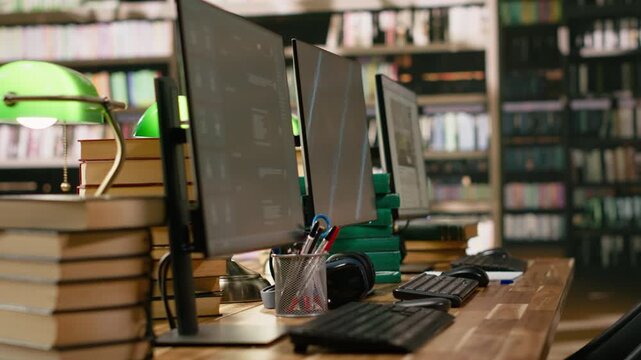 Desktop monitors with blue screen and AI chatbot in library workspace, data automation and abstract display background at desk, wooden table with headphones and books, for academic research.