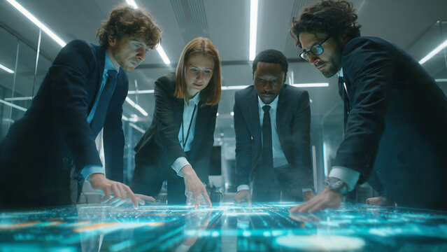 Diverse team collaborating around futuristic interactive display with glowing data, concept for technology, corporate strategy and digital innovation