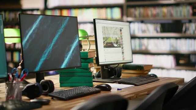 Business conference screen with abstract blue background and chatbot on two monitors at library study desk with keyboard, books and headphones, academic workspace, for education technology.