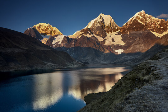 At the edge of Carhuacocha lagoon, the great triumvirate of the Cordillera Huayhuash reveals itself in a reflection of almost unbearable clarity. Siula Grande, Yerupaj&aacute; and Jirishanca rise in savage, 