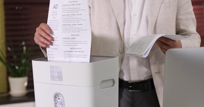Man destroying documents with shredder in office, closeup